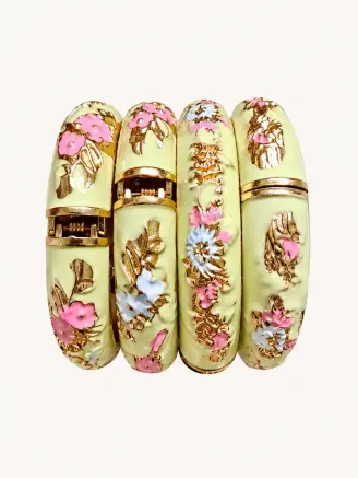 Cream enamel metal bangles featuring pink and blue floral designs with intricate golden detailing.